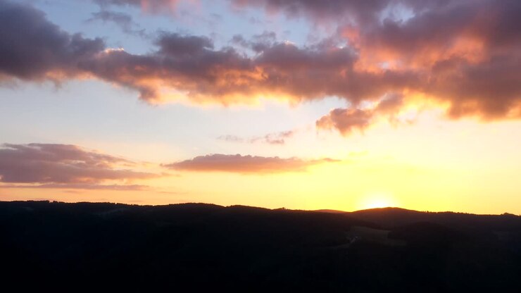 Timelapse del tramonto e nuvole rosse che scompaiono dietro le montagne nella Foresta Nera, Germania, vista come ripresa aerea in 4k