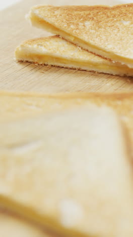 video de rebanadas de sándwiches de pan blanco con queso tostado en el fondo de la tabla de cortar de madera