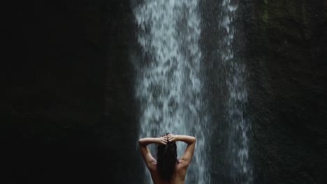 beautiful girl in bikini looks at the waterfall