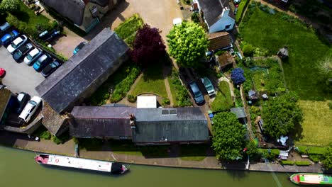 Die-Neigung-Aus-Der-Luft-Entlang-Des-Kanals-Zeigt-Das-Malerische,-Idyllische-Dorf-Stoke-Bruerne-In-England