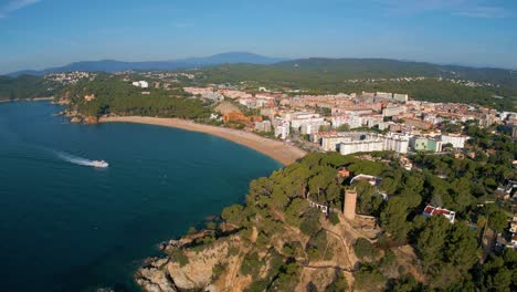 stunning aerial views from helicopter of fenals beach on the costa brava of girona blue sky passenger boat in front of the beach