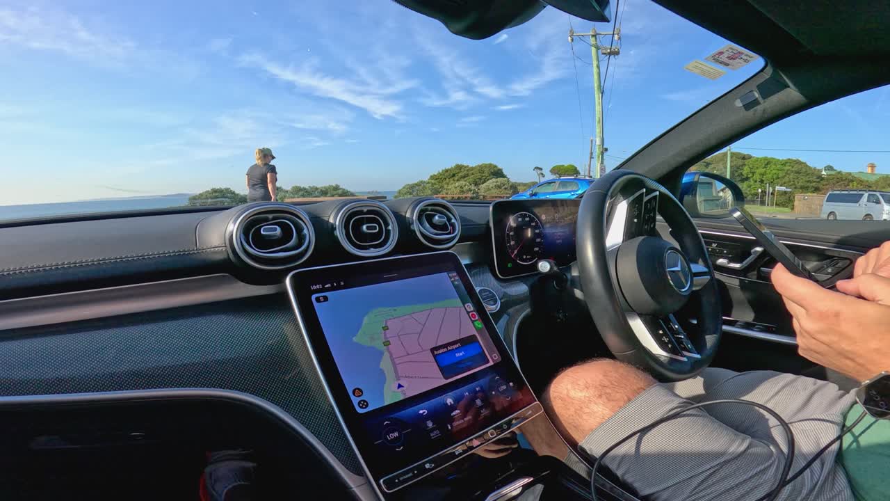 Interior car view with driver navigating Point Lonsdale, showcasing clear skies and coastal scenery