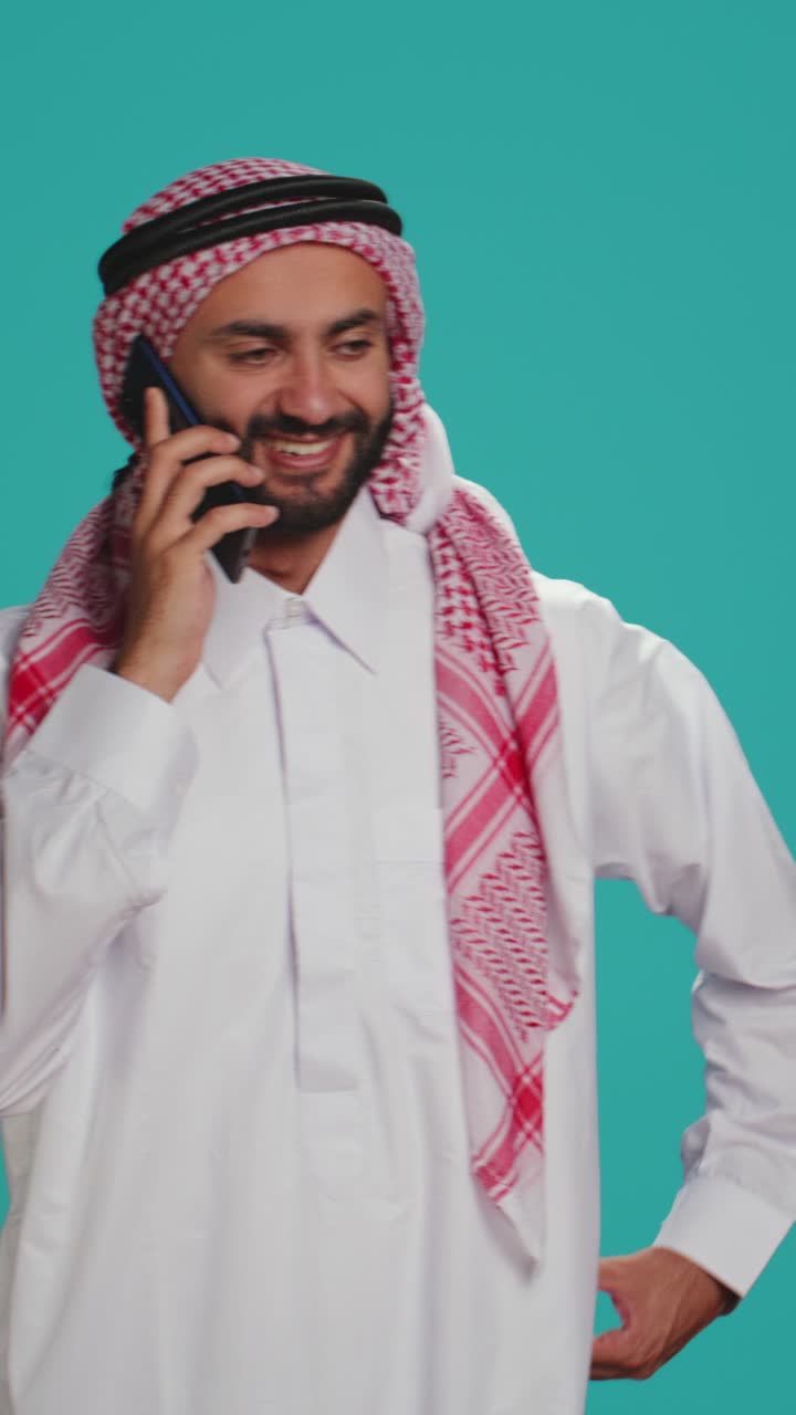 Pystyvideo islamilaisesta miehestä kaavussa tekstiviestien kirjoittamassa puhelimella