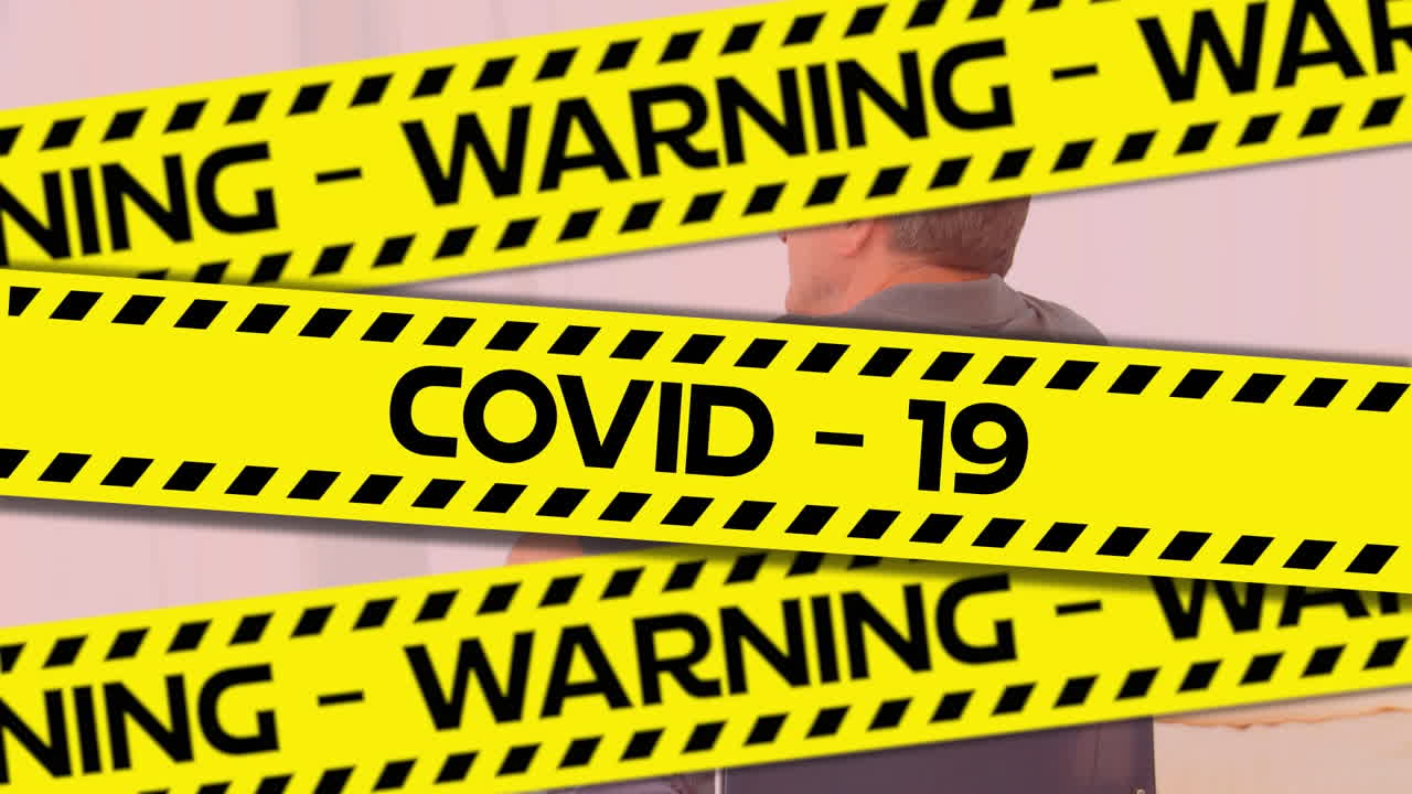 Words Warning Covid-19 written on yellow tape over a senior man  in background. Covid-19 spreading