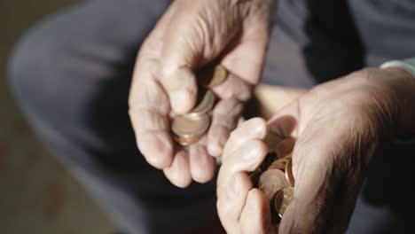 despair old man holding in his wrinkled hands stack of euro coins, pensioner counting his miserable pension and putting currency from one hand paw to another. problem of low pension among people in