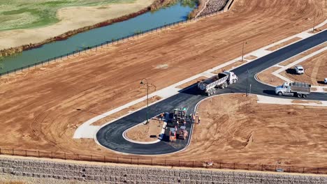 Vista-Aérea-De-Un-Equipo-De-Pavimentación-De-Carreteras-Que-Trabaja-Con-Una-Pavimentadora-De-Asfalto-Y-Un-Camión-En-El-Nuevo-Sitio-De-La-Carretera