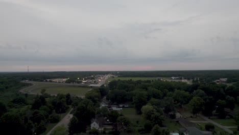 aerial drone shot over small town homes on both sides of a road, set among dense vegetation at sunset