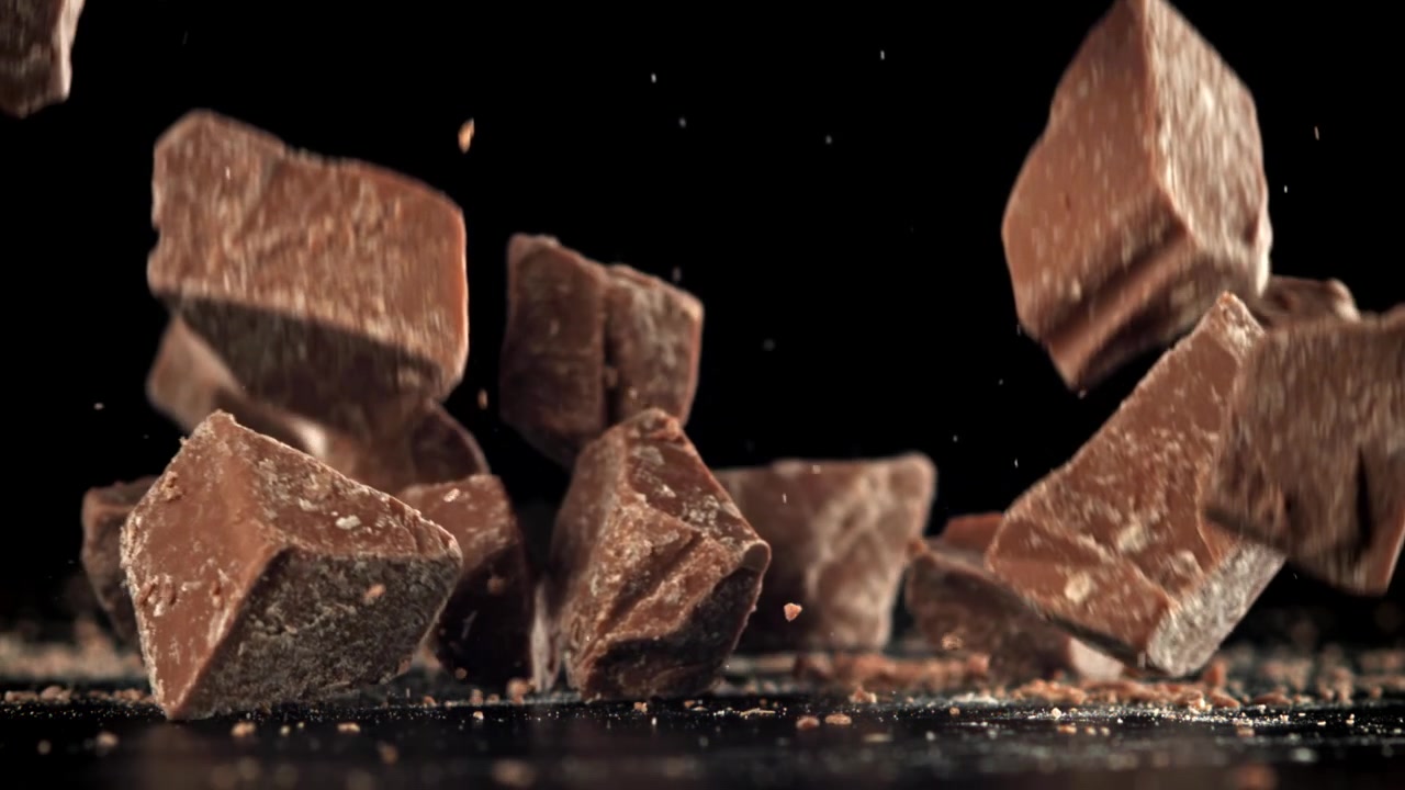 Movimento rallentato di pezzi di cioccolato che cadono su sfondo nero