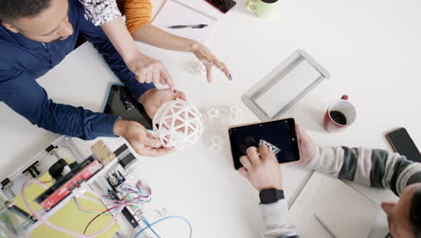 Vista-Superior-De-Una-Reunión-De-Negocios-Creativa,-Un-Hombre-De-Negocios-Usando-Una-Tableta-Que-Muestra-Una-Forma-Impresa-En-3D-Para-Un-Ingeniero-Discutiendo-Un-Nuevo-Diseño-En-Una-Moderna-Sala-De-Juntas