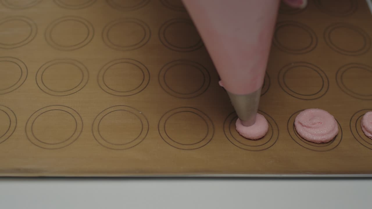 cerca de verter la masa de almendra rosa con la bolsa de pastelería para cocinar las galletas de macarrón. cerca, en cámara lenta.