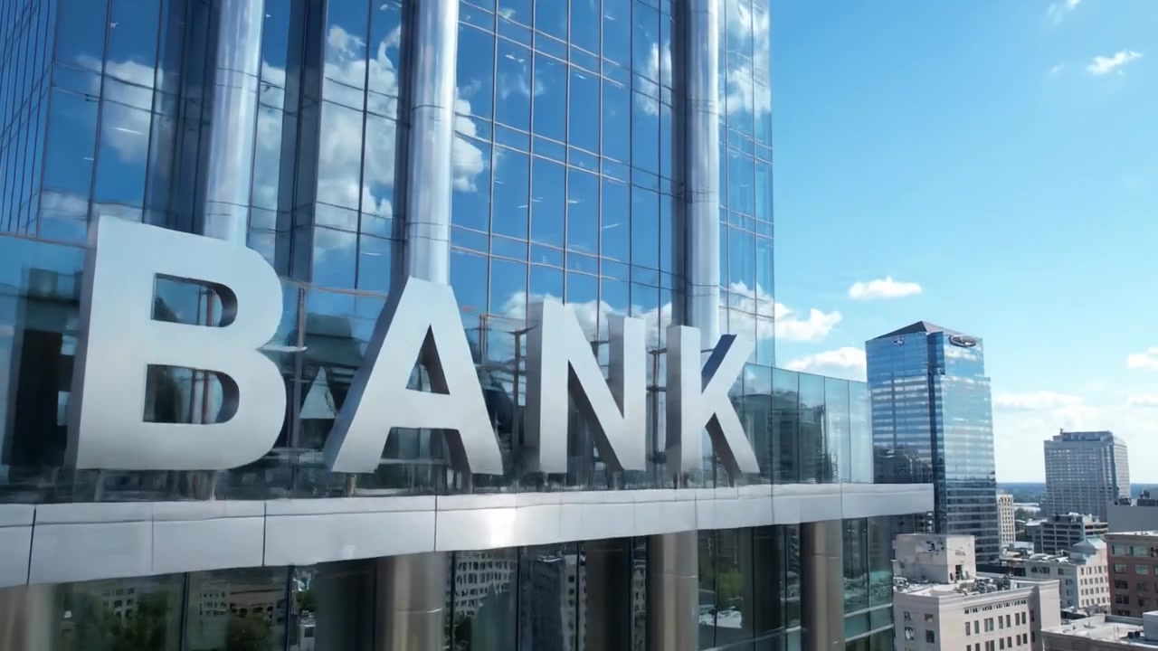 Uma Visão Geral Deslumbrante da Arquitetura Moderna Apresentando um Edifício Bancário Reflexivo Cercado por um Skyline Urbano e Céus Azuis Claros.
