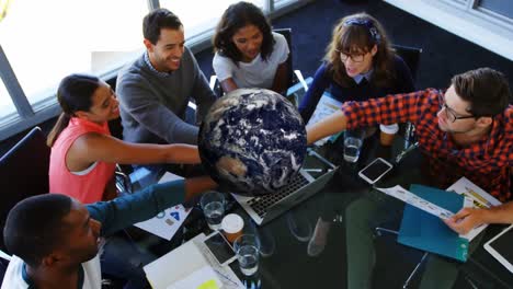 animation of rotating globe over group of diverse business team holding hands