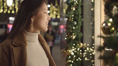 woman window shopping at night during christmas