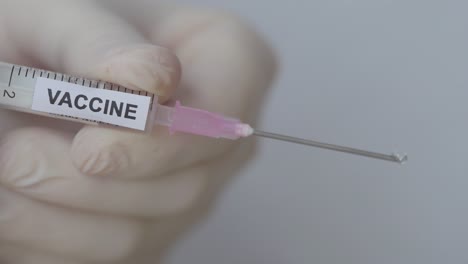 vaccine fluids dropping from needle of disposable syringe