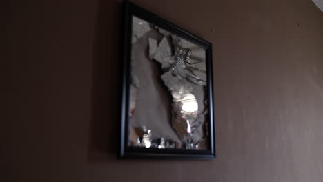 Broken,-shattered-glass-mirror-hanging-on-the-wall-inside-a-home