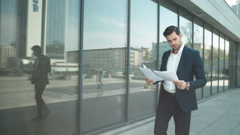 Closeup-businessman-walking-with-papers-at-street.-Businessman-reading-documents