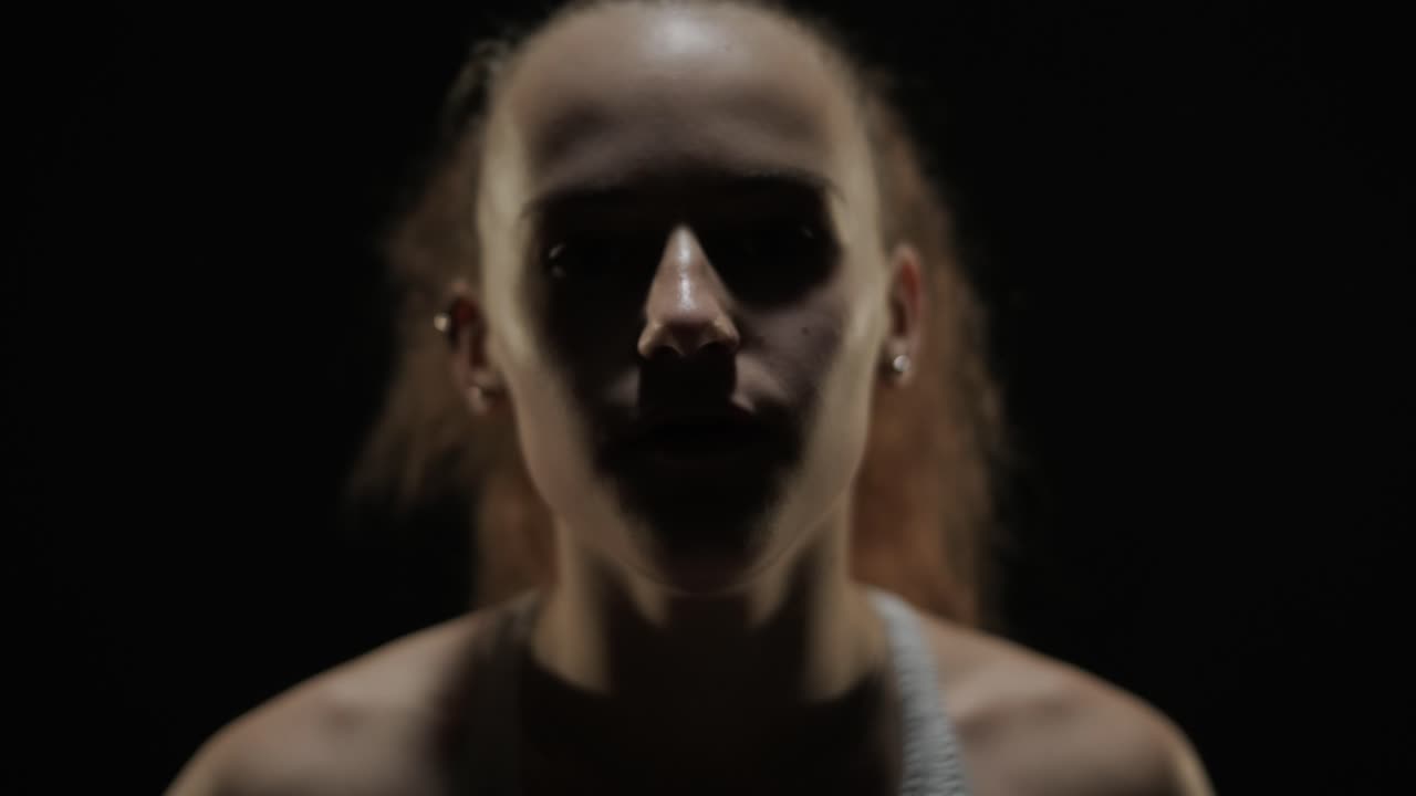 un grupo de bailarines profesionales están practicando capoeira en la oscuridad contra un foco de luz en un fondo negro de estudio. arte marcial afro-brasileño que combina elementos de la danza.