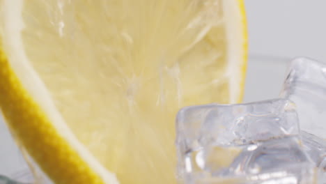 cold fresh sparkling water poured into a glass with ice and lemon slices