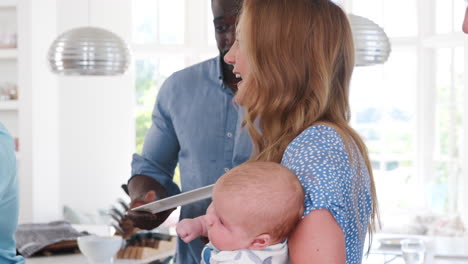 Slow-Motion-Shot-Of-Multi-Generation-Family-And-Friends-Gathering-In-Kitchen-For-Celebration-Party