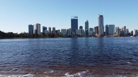 drone shot rising over swan river with view of skyline of perth, western australia