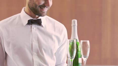 smiling waiter holding champagne bottle and flute