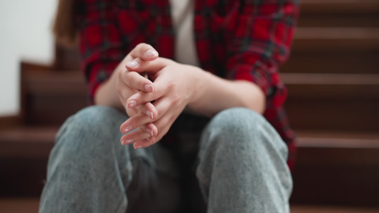 Woman rubs palms sitting on steps closeup. Girlfriend prepares to breakup with abusive boyfriend on staircase. Nervous lady deals with panic attack