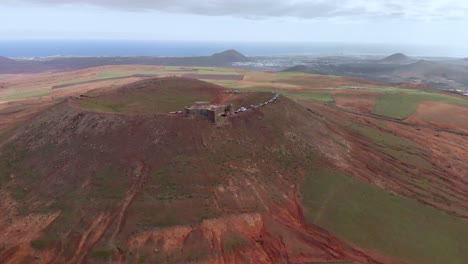 retira la foto de un dron de un castillo en el borde de un volcán rojo