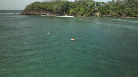 drone view of surfers sitting on their boards while in the waters of the shallow reef of mt irvine, tobago