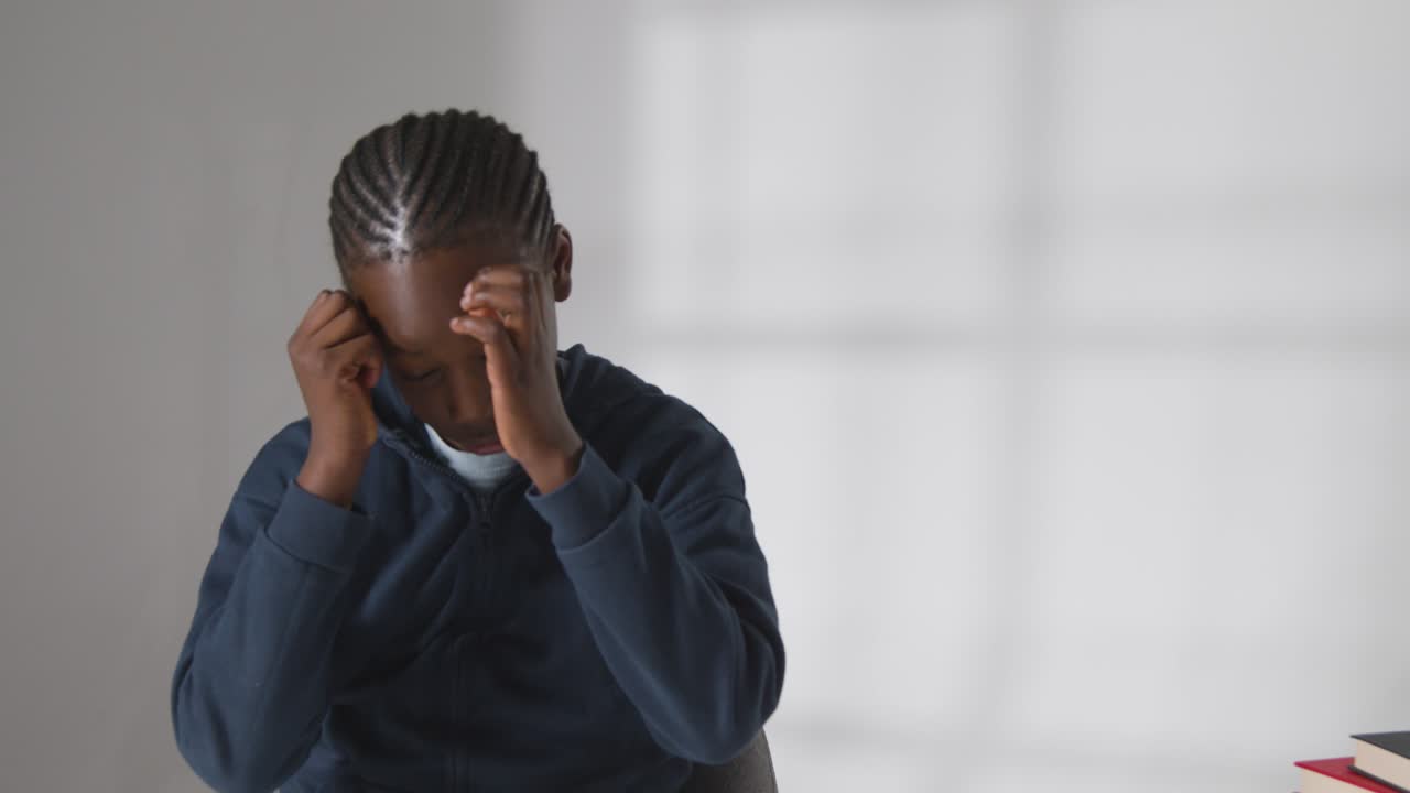Studio Shot Of Boy At Table Struggling To Concentrate On School Book 5