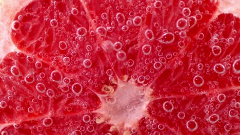 half of a ripe grapefruit under water with air bubbles.