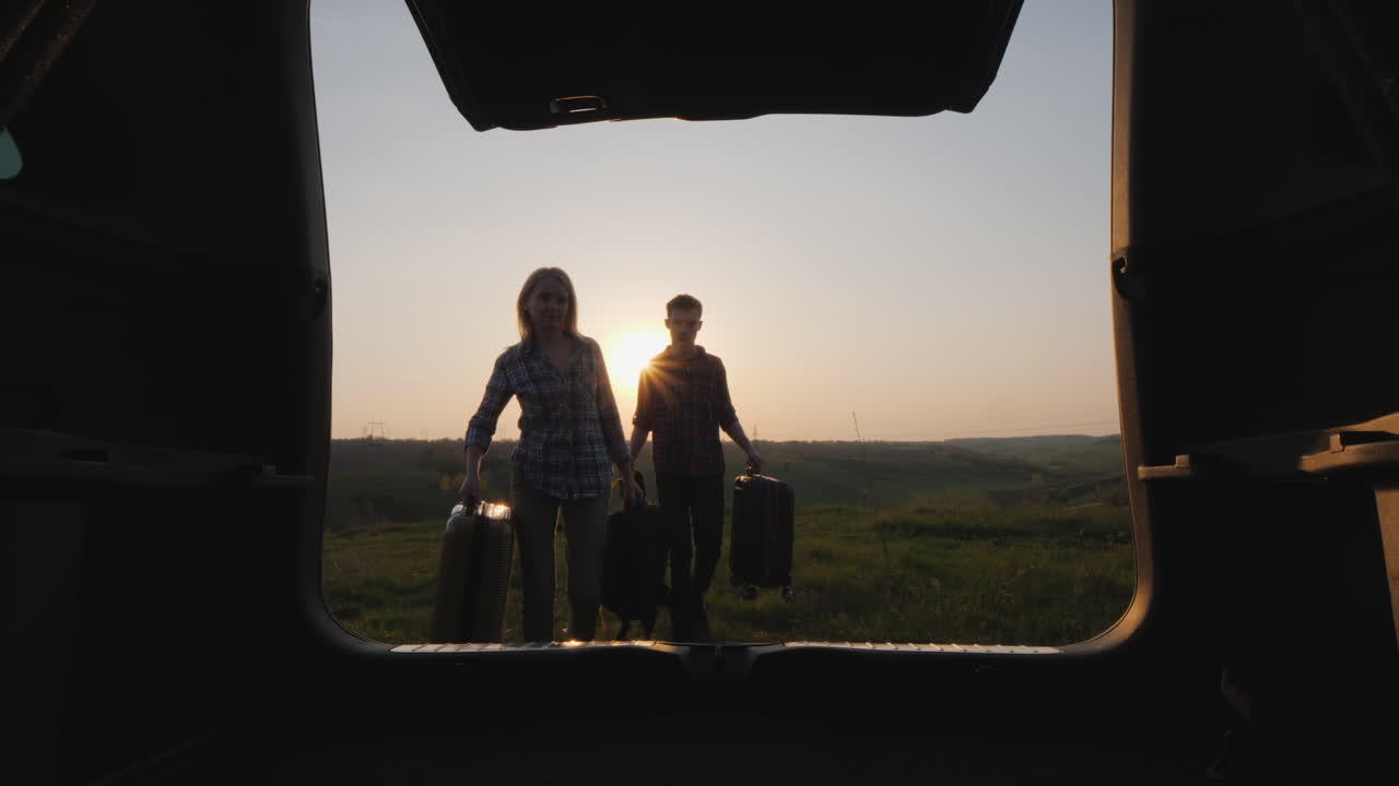 A Pair Of Tourists Loads Bags In The Trunk Of A Car