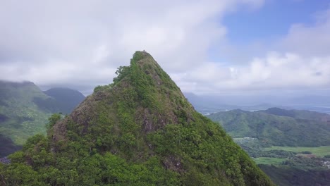 Bright-green-mountain-top-on-Windward-side,-east-of-Honolulu,-Oahu-Hawaii-with-bright-blue-sky,-aerial-orbit