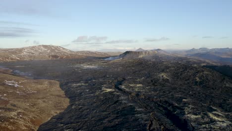 tiro de dron ascendente que muestra el paisaje del volcán y geldingadalir en erupción durante un día soleado con cielo azul en islandia