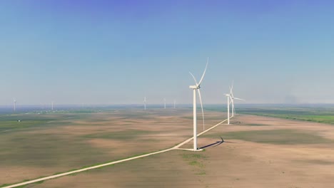 wide aerial shot, wind turbines, wind power station, farmland landscape, drone flying, wind farm on sunny day, blue sky, hazy morning, overview flight, green energy, san roman windfarm, texas