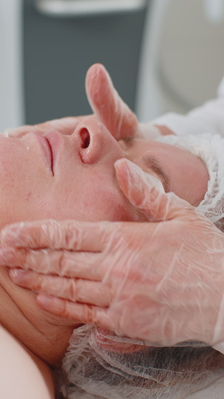 Estetista che applica una crema idratante speciale per il peeling del viso di una graziosa donna caucasica