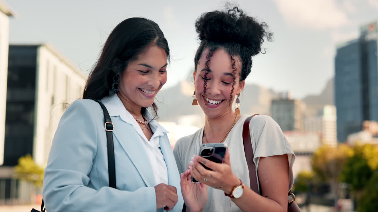 dos mujeres de negocios mirando un teléfono inteligente