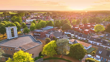 beautiful light of sunset dazzling a scenery of picturesque residential area. drone flight over the cemetery and church in overloon, netherlands