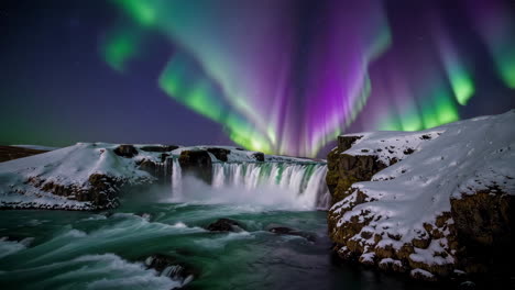 northern lights over a snowy waterfall at night