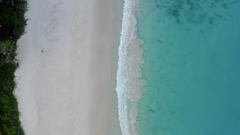 Top-down-aerial-view-of-big-waves-crashing-against-the-shore