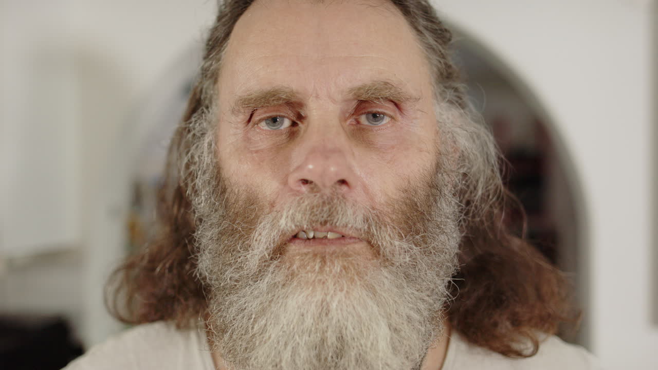 Ungroomed bearded man with neutral facial expression, frontal portrait