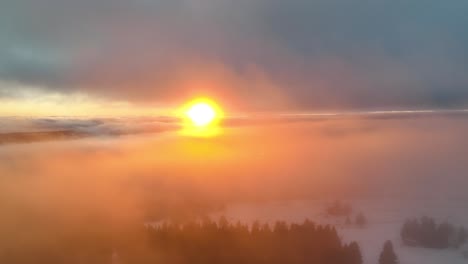 cinematic sunset over the winter clouds and the forest - aerial view