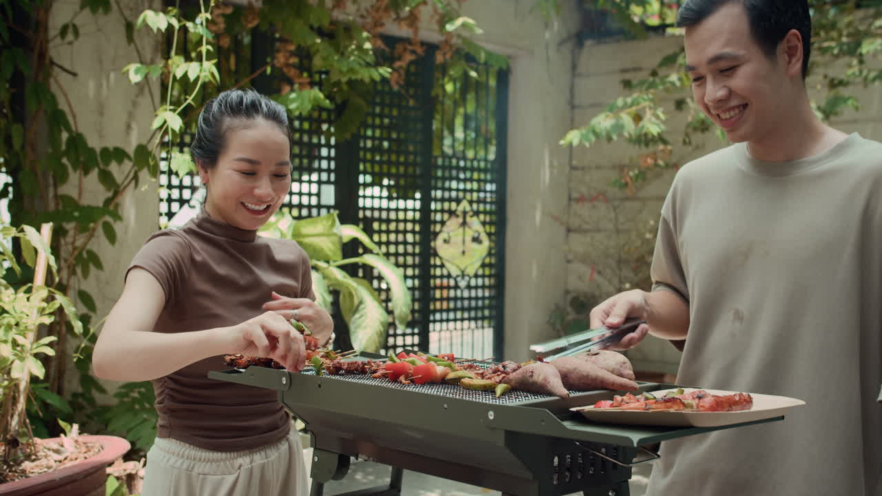Guy Tasting Skewer from Hands of His Girlfriend during Barbecue Outdoors