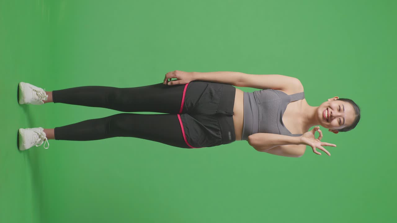 mujer en ropa deportiva dando una señal de ok contra la pantalla verde