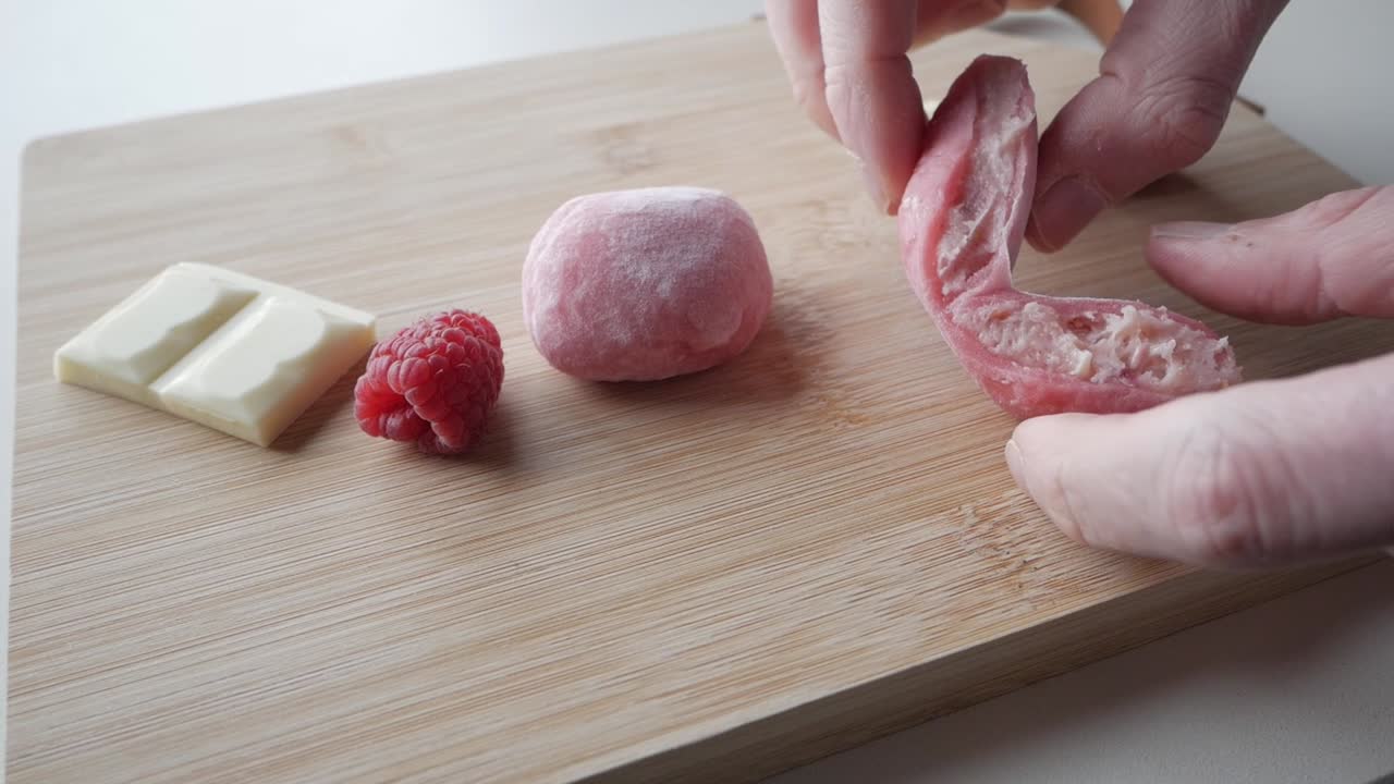 Fresh strawberry mochi with white chocolate and raspberries on a wooden board