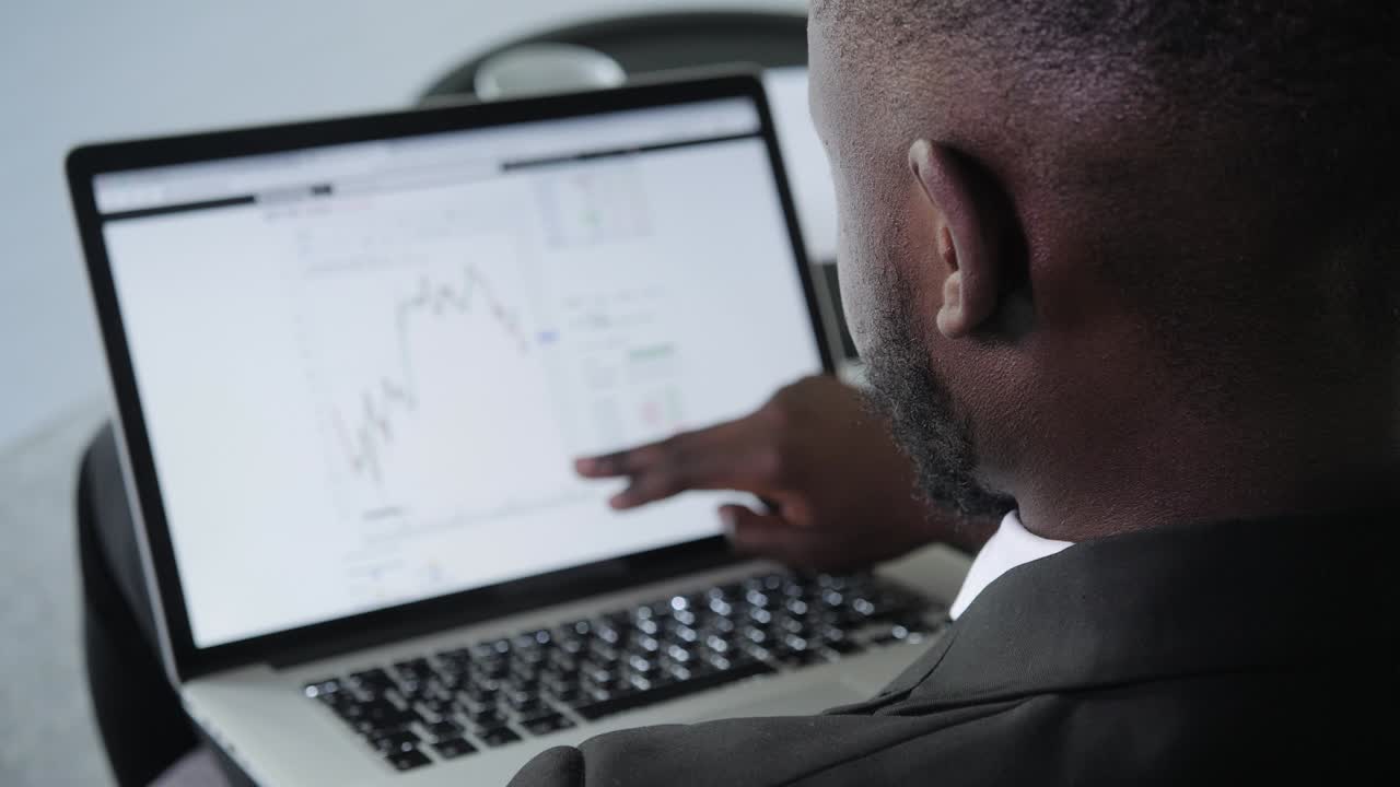 Black Businessman using laptop for analyzing data stock market, forex trading graph, stock exchange trading online, financial investment concept. close up