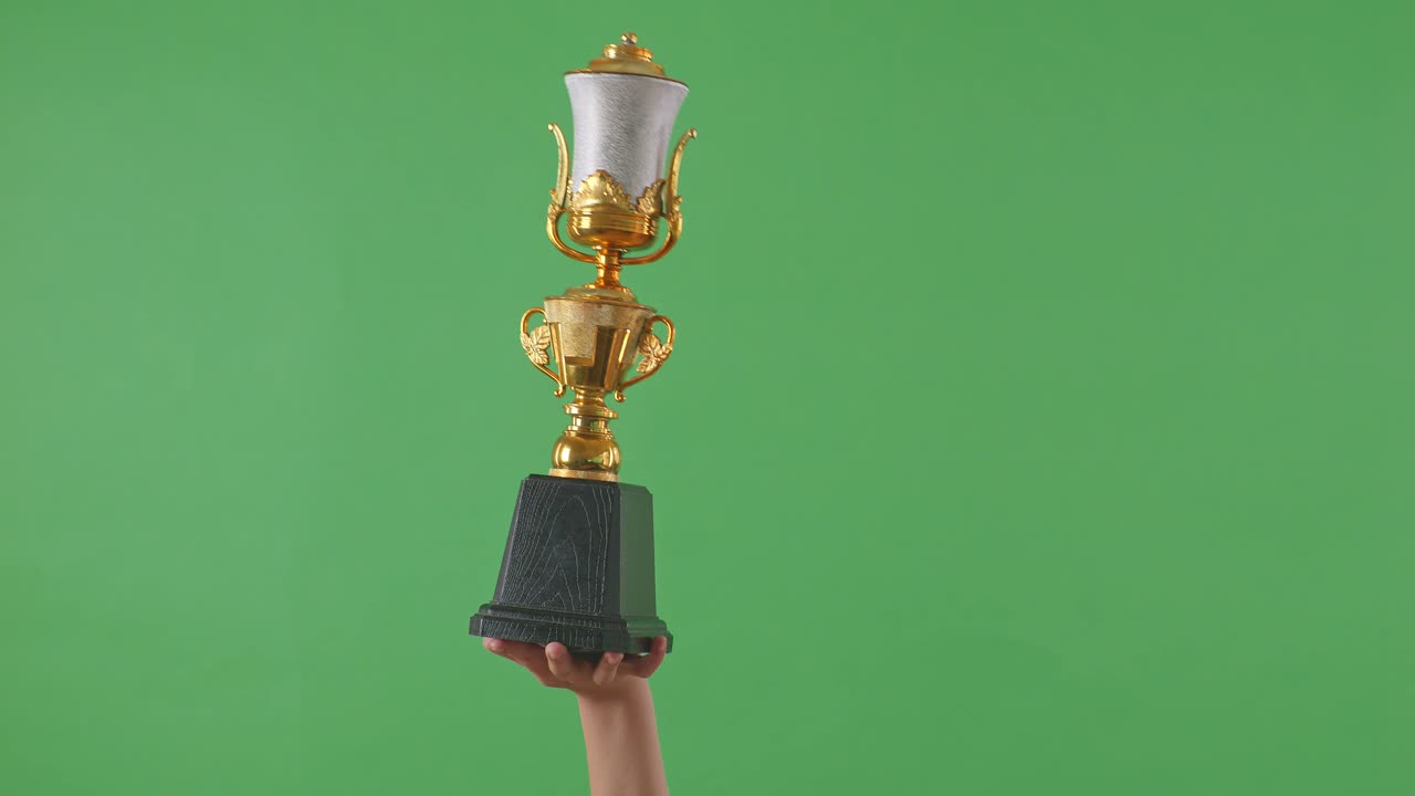 con el trofeo en la mano contra un fondo verde
