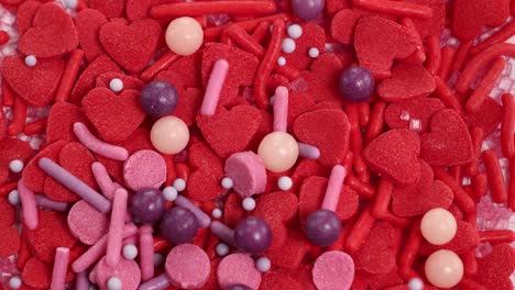 vibrant candy sprinkles cascade onto a base of red heart-shaped candies, creating a lively and colorful composition