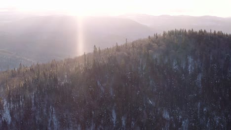 sunrise aerial flight over boreal forest and mountains through active snowstorm in quebec canada