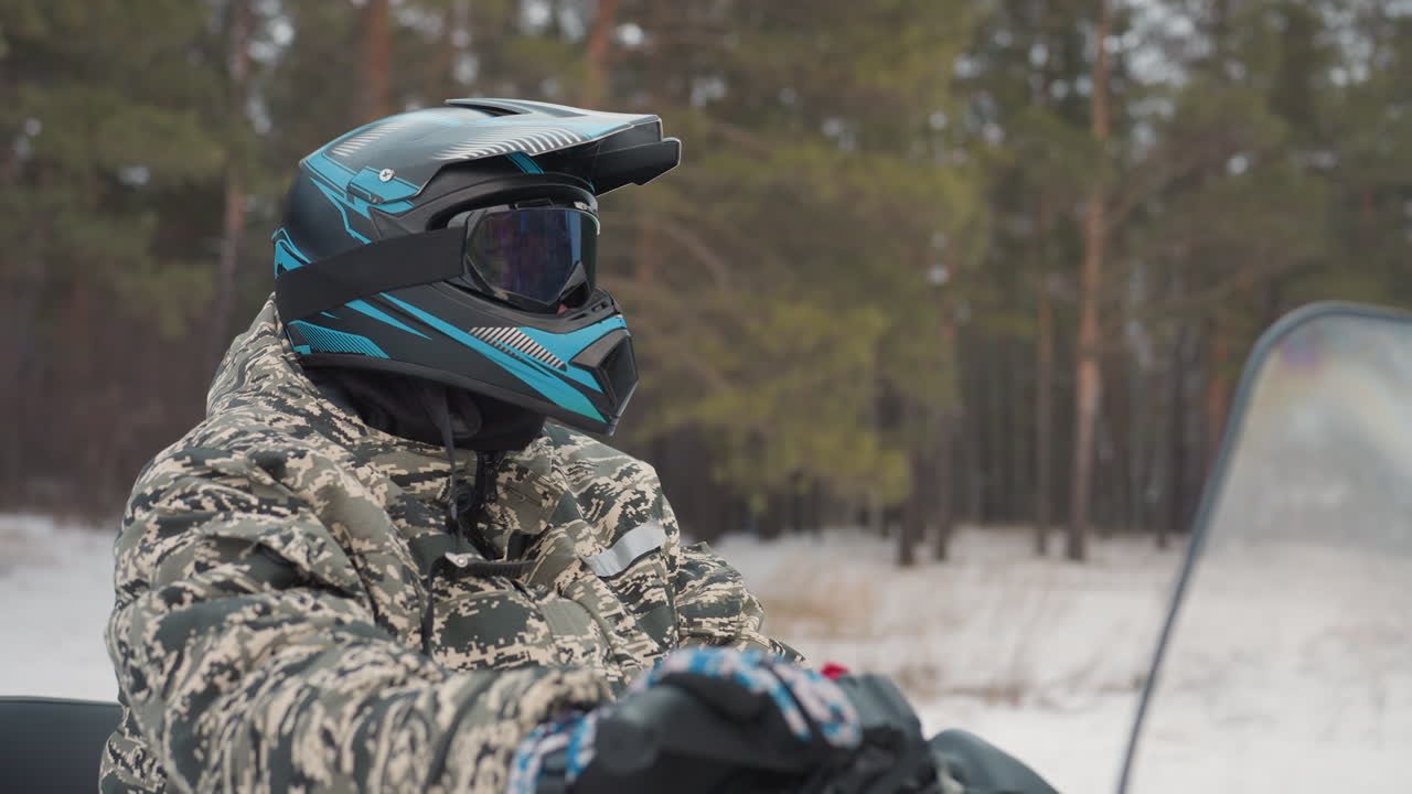 Kendinden emin sürücü kış ormanlarını keşfediyor. ATV, huzurlu karla kaplı ormanı yarıyor. Sakin ve soğukkanlı sürücü, panoramik manzaralı kamuflaj ceketiyle karlı ormanlarda ilerliyor.
