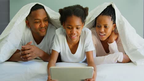 Vista-Frontal-De-Una-Familia-Negra-Feliz-Usando-Una-Tableta-Digital-En-La-Cama-En-Una-Casa-Cómoda-4k